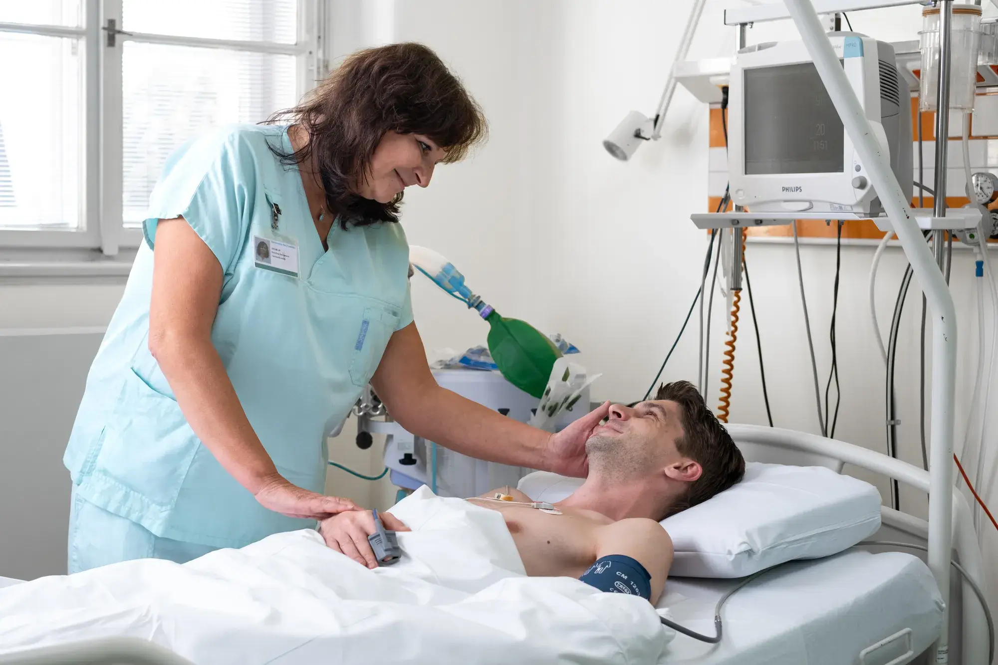 Sestra pečuje o pacienta na lůžku vedle monitoru