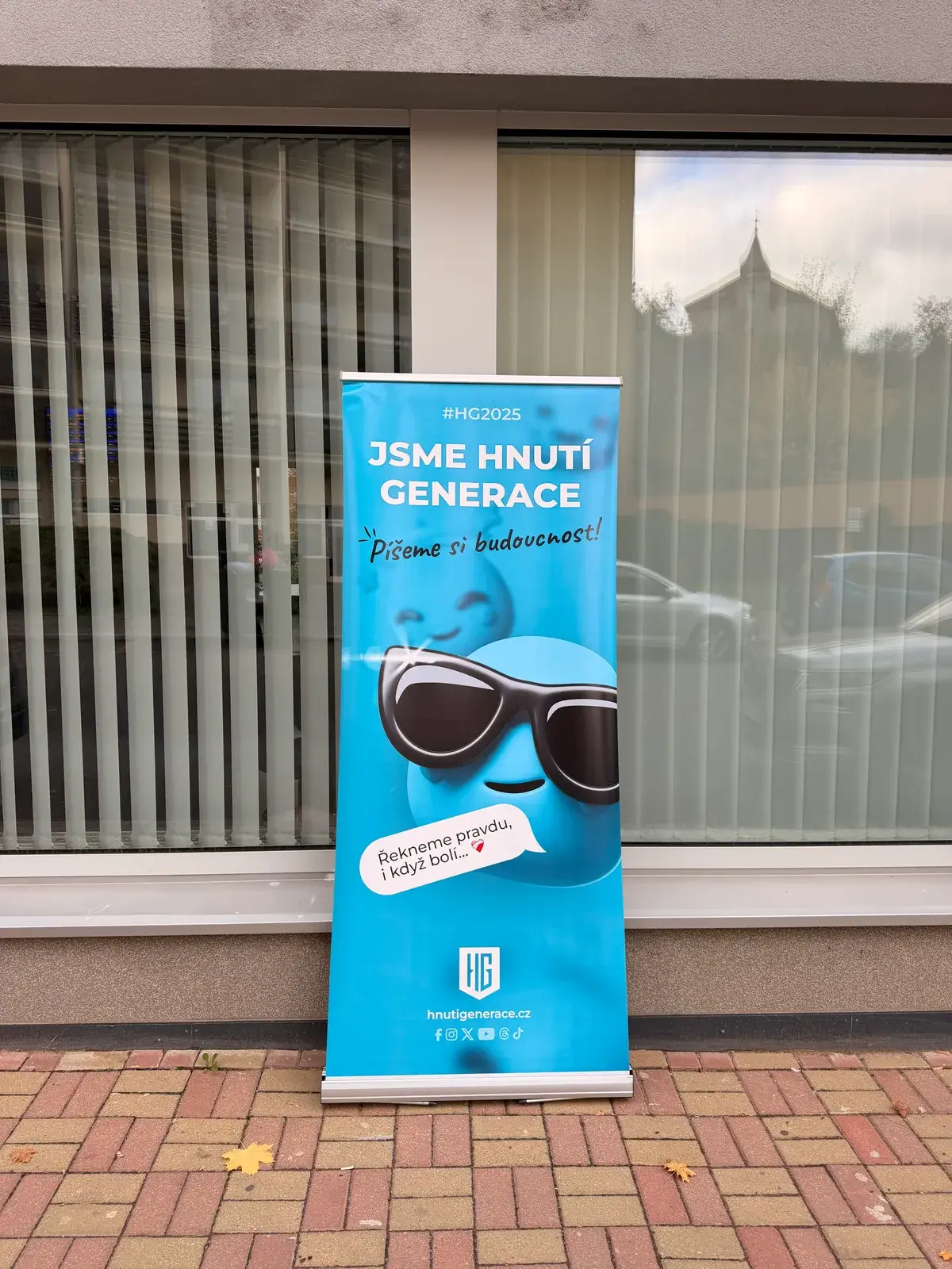 Vytištěný roll-up Hnutí Generace se smajlíkem před budovou